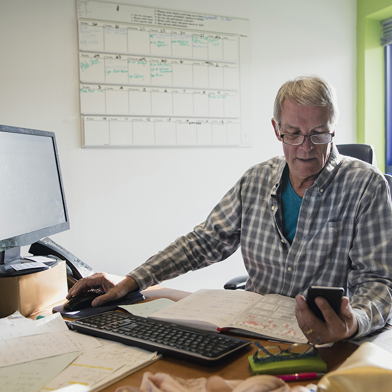 Man at desk checking his mobile phone