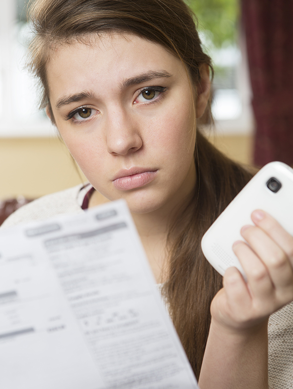 Girl holding mobile phone and phone bill