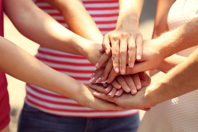 Group of people placing hands together in a circle