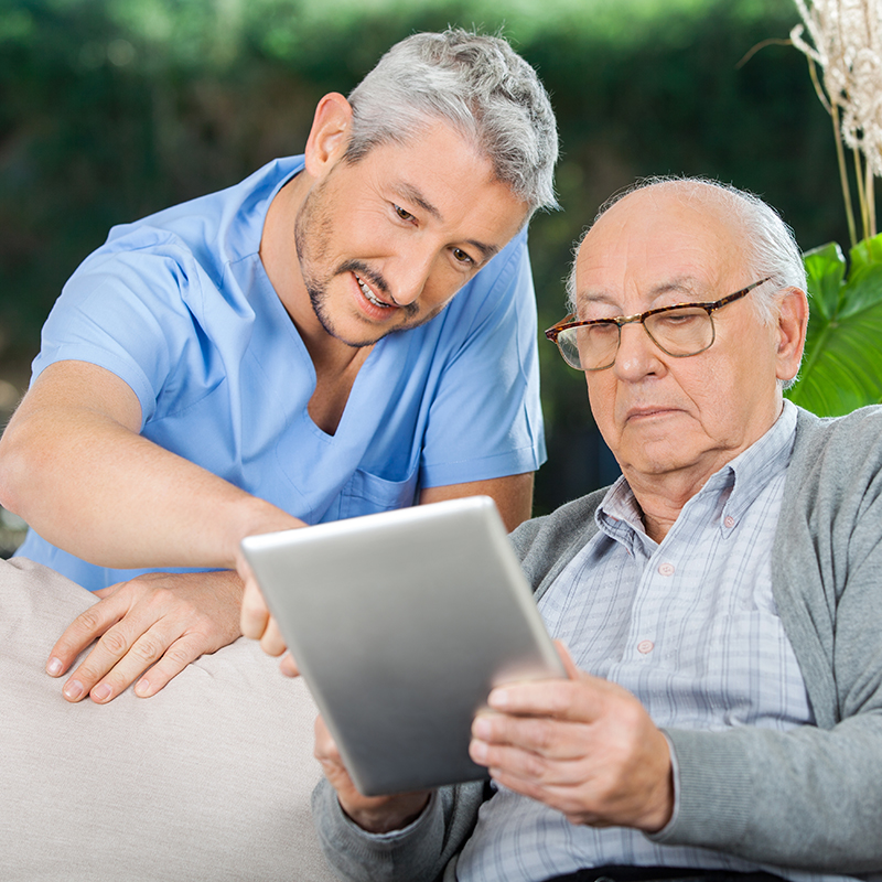 Doctor helping older man access the internet on tablet