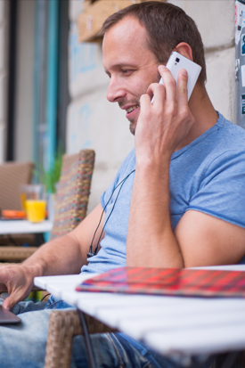 Man using mobile phone while typing on laptop