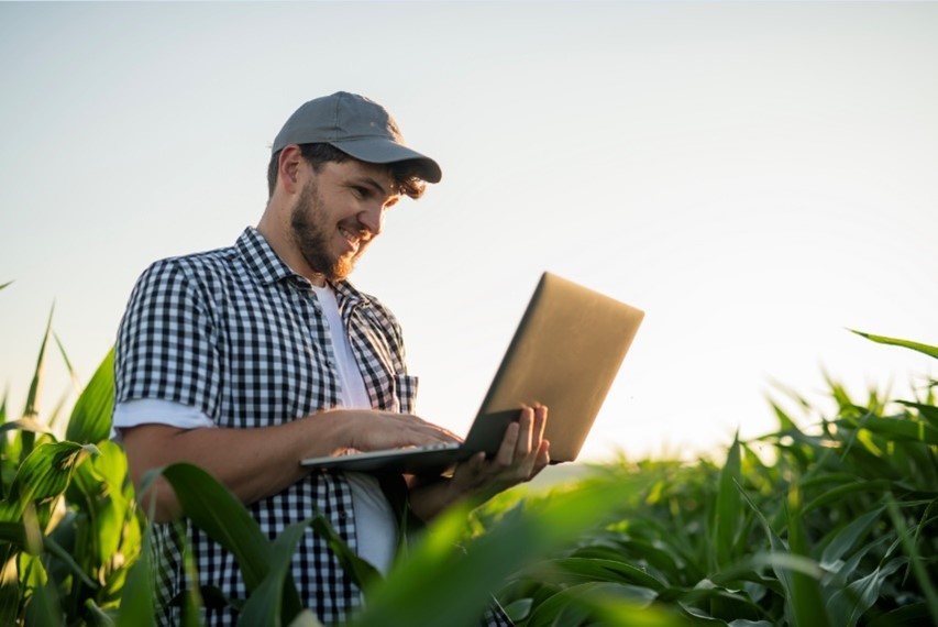 Farmer outstanding in his field with laptop