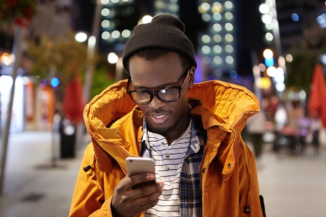 Man using smartphone on street at night