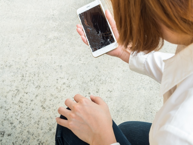 Girl holding smartphone with broken screen