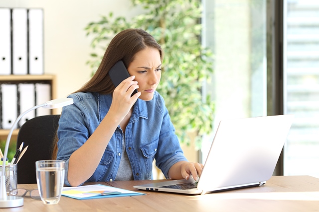 Female small business owner using phone and laptop