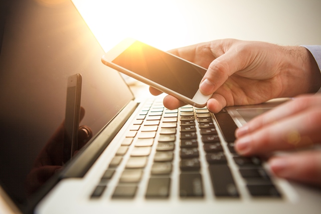 Person using smartphone and laptop