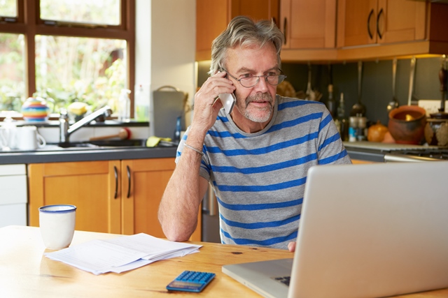 Man looking at computer while talking on phone