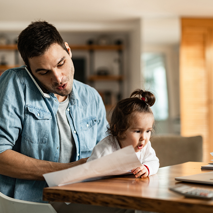 Man working at home with daughter on lap