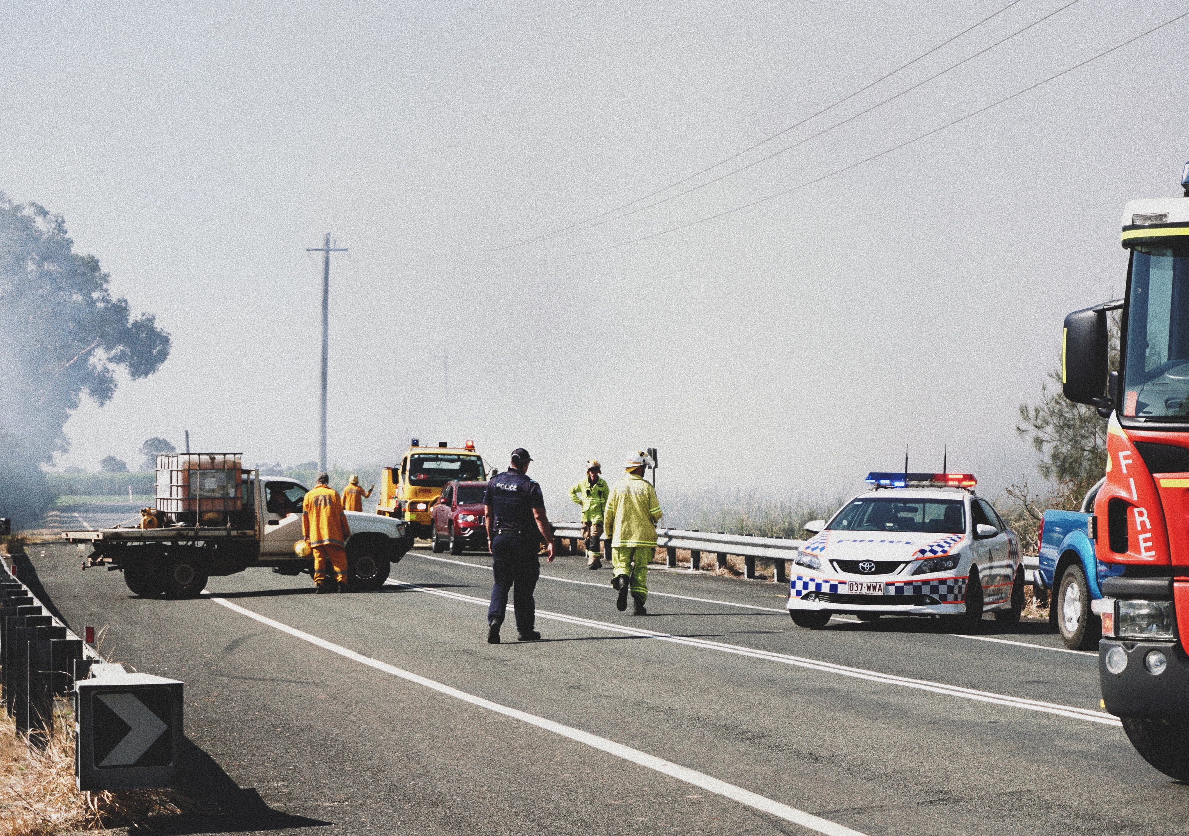 Image of a fire truck, police officers and a police car responding to an incident on a road