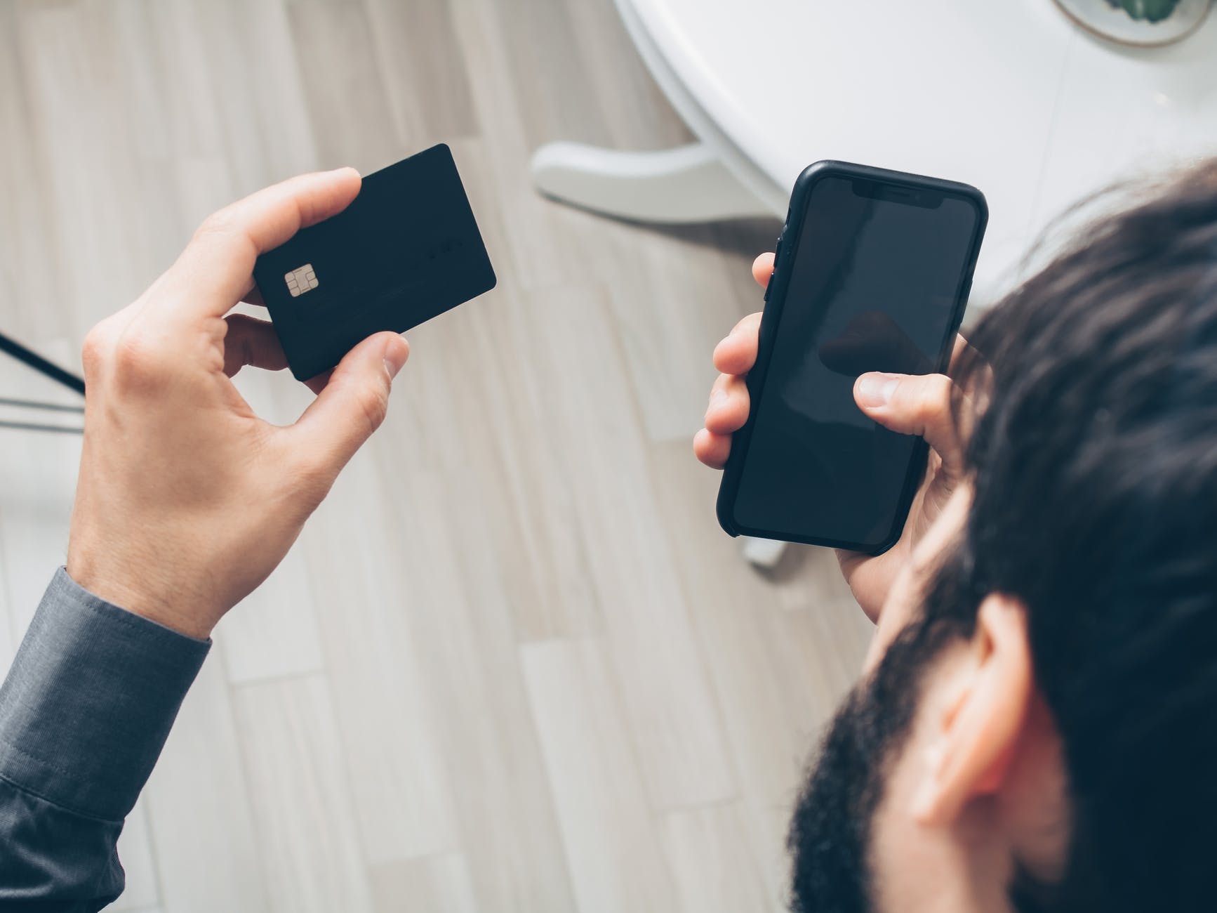 A man holding a credit card in one hand, and a phone in the other 